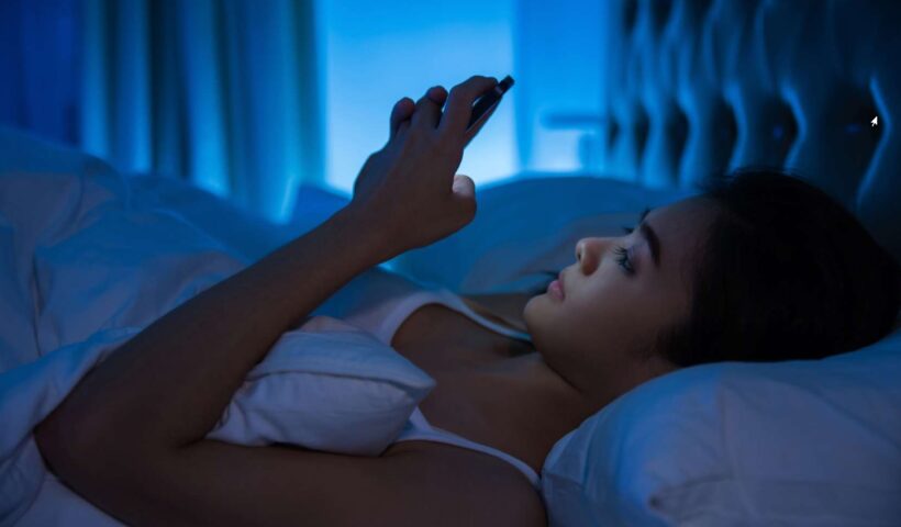 Femme allongée dans son lit avec son téléphone